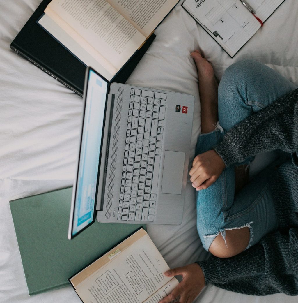 Persona estudiando en casa con portátil, libros y agenda